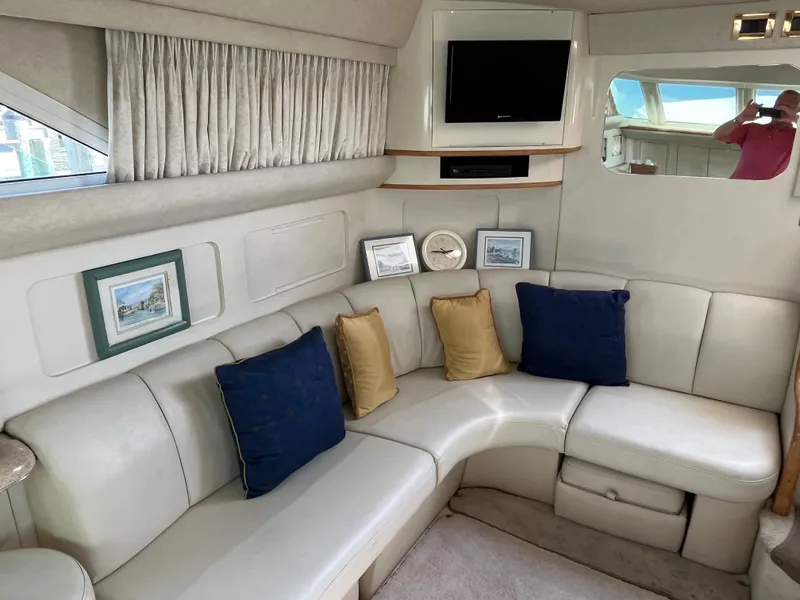 Slide: The Image of 1997 Sea Ray 420 Aft Cabin interior with white leather seating, TV, and decorative pillows. - 26