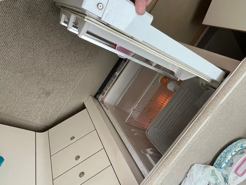 Slide: The Image of 1997 Sea Ray 420 Aft Cabin interior showing an open refrigerator and cabinetry. - 28