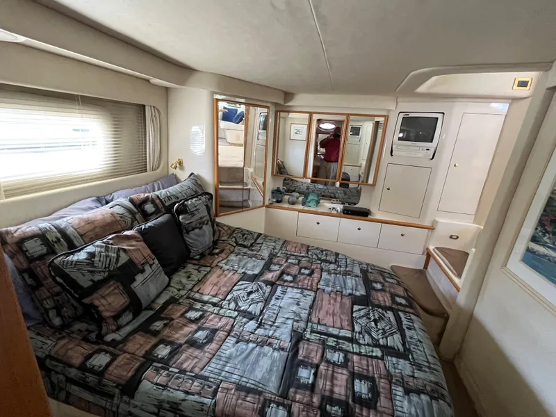 Slide: The Image of 1997 Sea Ray 420 Aft Cabin bedroom with patterned bedding and ample storage. - 35