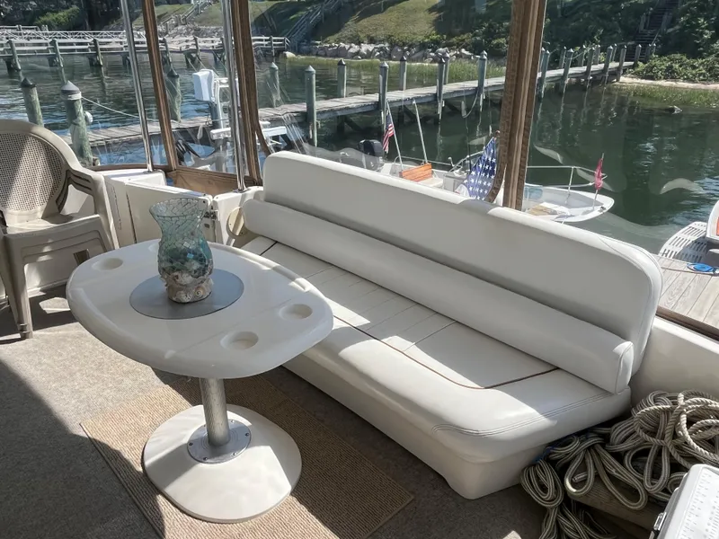 Slide: The Image of 1997 Sea Ray 420 Aft Cabin interior with white seating and table by the dock. - 9