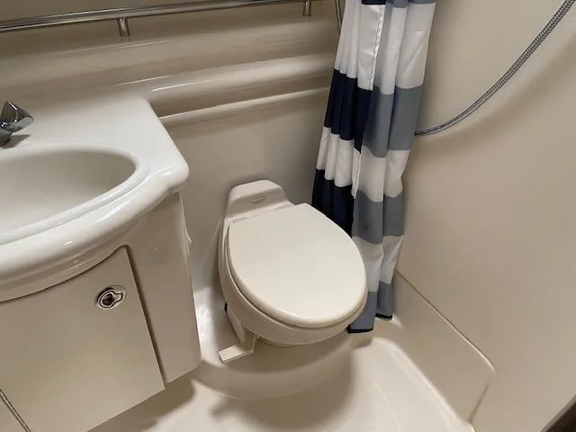 Slide: The Image of 2005 Maxum 3500 SY boat bathroom with sink, toilet, and striped shower curtain. - 17