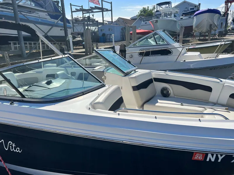 Slide: The Image of 2013 Chaparral 246 SSi boat docked at a marina, featuring a sleek design and spacious seating. - 4