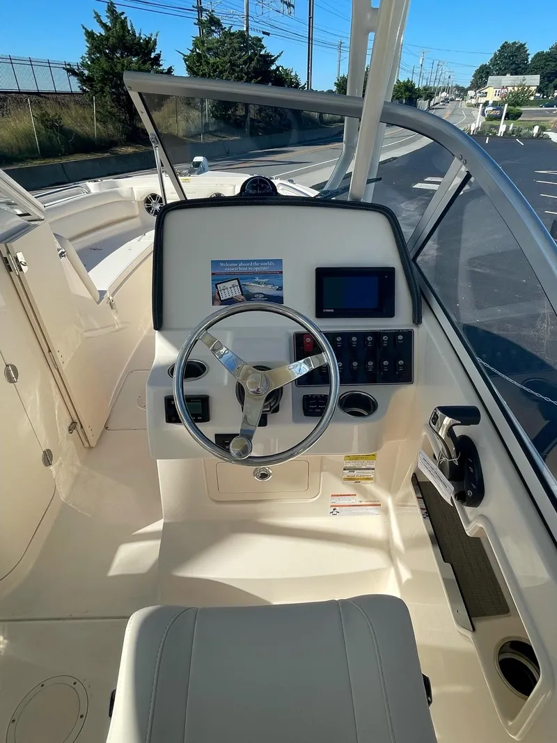 Slide: The Image of 2024 Grady-White Freedom 235 boat cockpit with steering wheel and control panel. - 2
