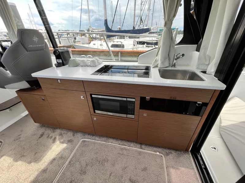 Slide: The Image of Modern kitchen area in 2022 Jeanneau NC 1095 boat with sink, stove, and microwave. - 12
