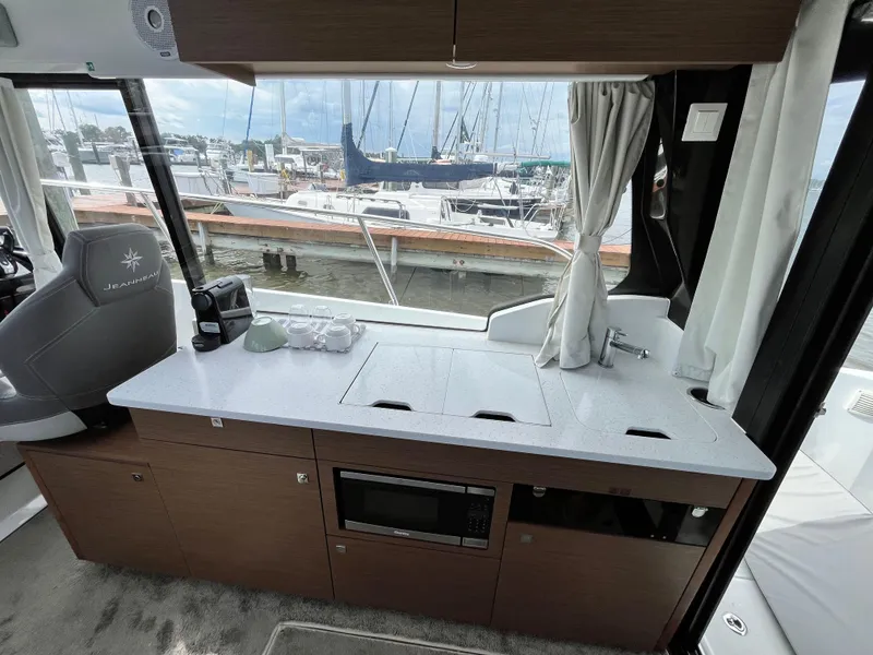 Slide: The Image of Jeanneau NC 1095 2022 yacht interior with kitchenette and marina view. - 13