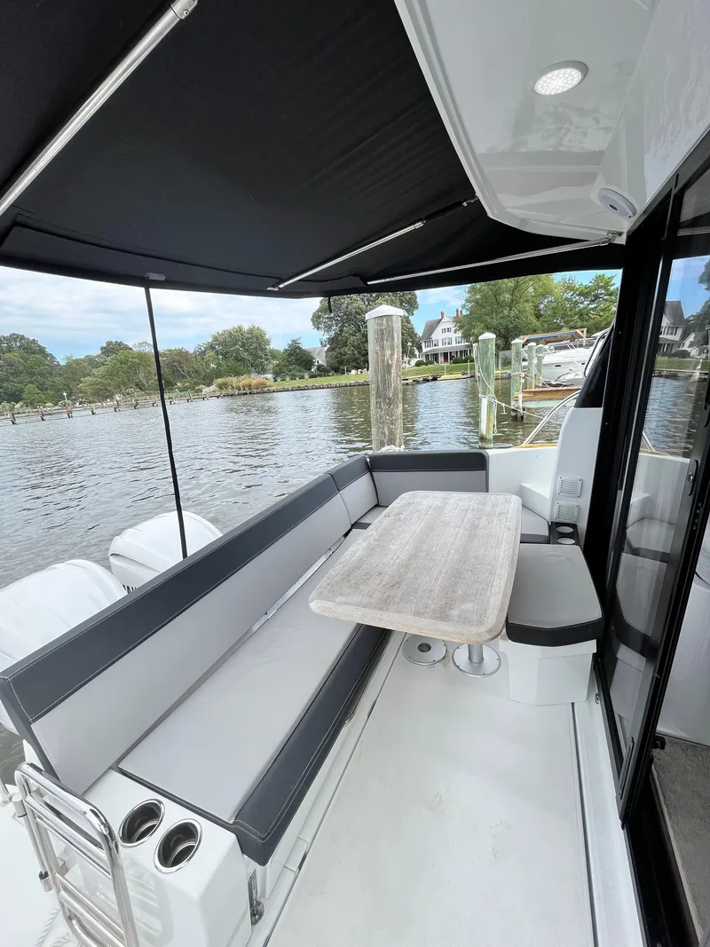 Slide: The Image of 2022 Jeanneau NC 1095 boat with outdoor seating and table by the water. - 15