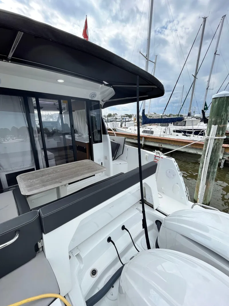 Slide: The Image of 2022 Jeanneau NC 1095 boat docked, featuring outdoor seating and twin engines. - 16