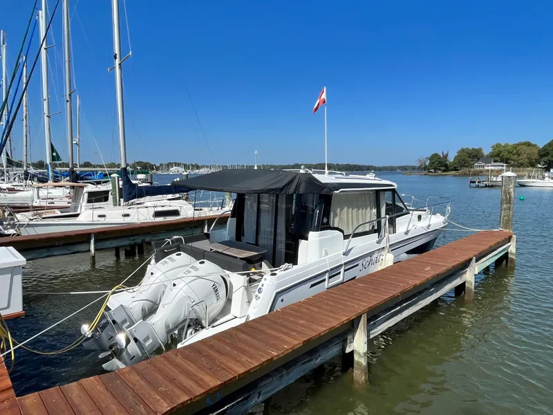 Slide: The Image of 2022 Jeanneau NC 1095 docked at marina under clear blue sky. - 2