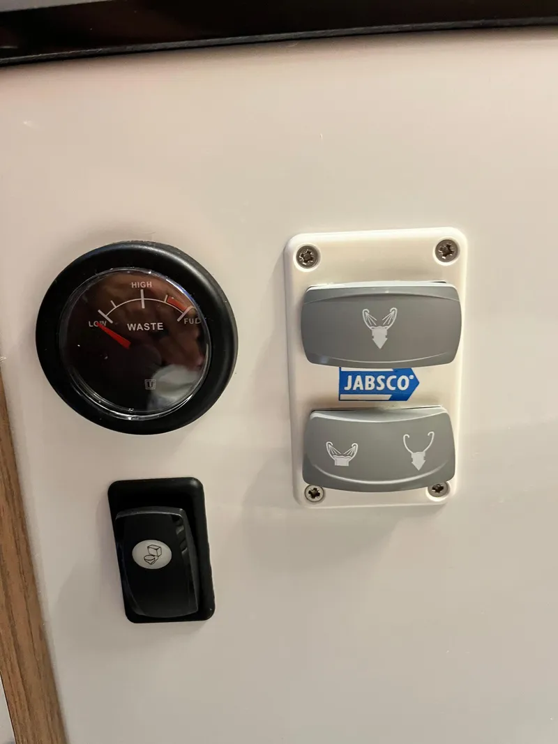 Slide: The Image of Control panel of 2022 Jeanneau NC 1095 boat with Jabsco switches and waste gauge. - 24