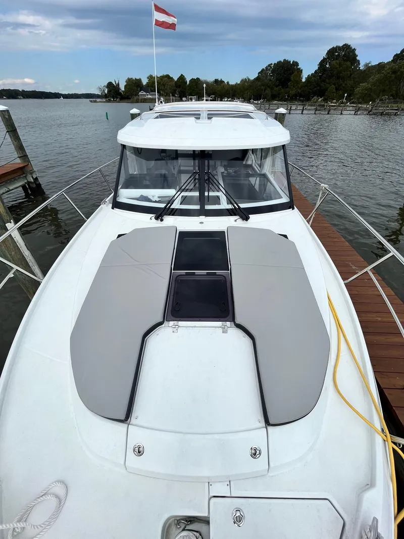 Slide: The Image of 2022 Jeanneau NC 1095 boat docked on a serene lake with a flag. - 3