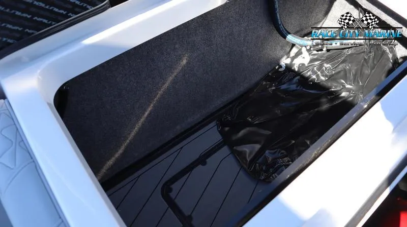 Slide: The Image of 2024 Nautique GS24 storage compartment with black interior and Race City Marine logo. - 22