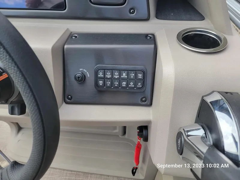Slide: The Image of Control panel of 2024 Sun Tracker SportFish 22 DLX boat, featuring various switches and a cup holder. - 20