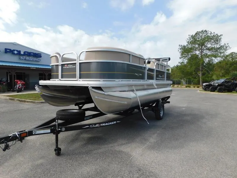 Slide: The Image of 2024 Sun Tracker Party Barge 18 DLX pontoon boat on trailer in dealership lot. - 2