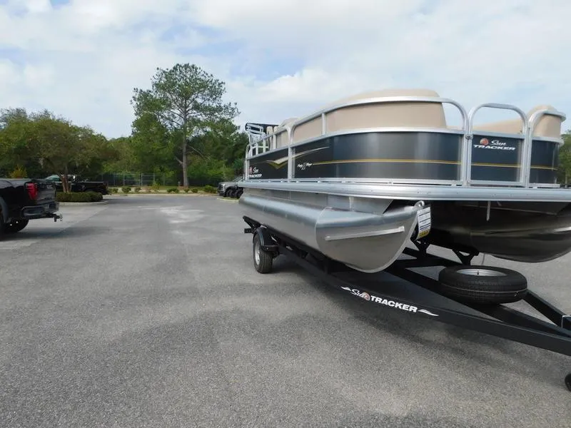 Slide: The Image of 2024 Sun Tracker Party Barge 18 DLX pontoon boat on a trailer in a parking lot. - 3
