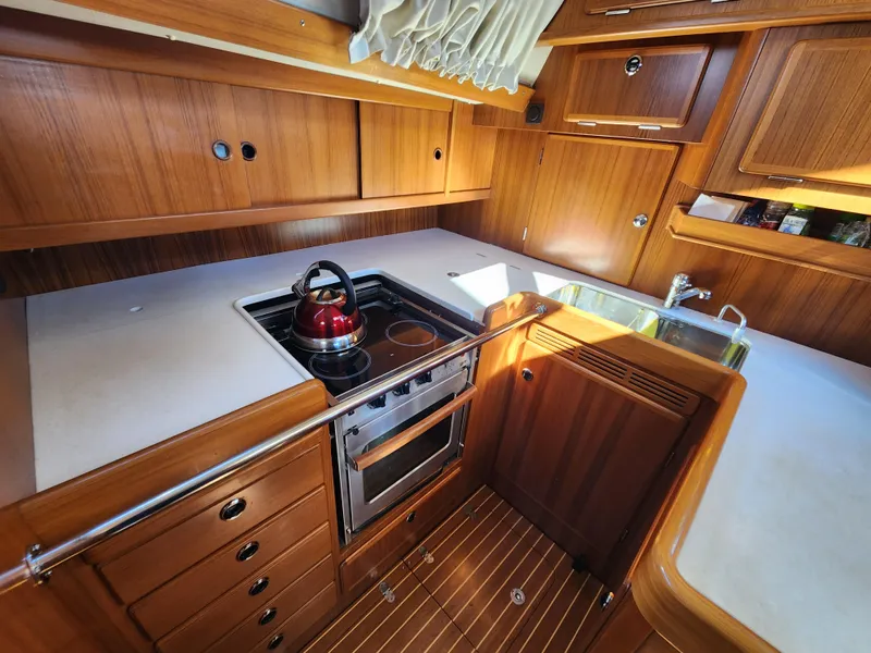 Slide: The Image of 2006 Hallberg-Rassy 53 yacht kitchen with stove, sink, and wooden cabinetry. - 19