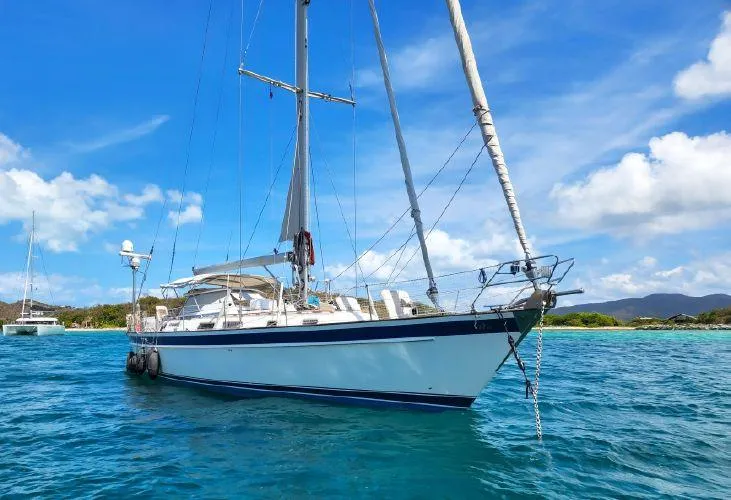 Slide: The Image of 2006 Hallberg-Rassy 53 sailboat anchored in clear blue waters under a sunny sky. - 2