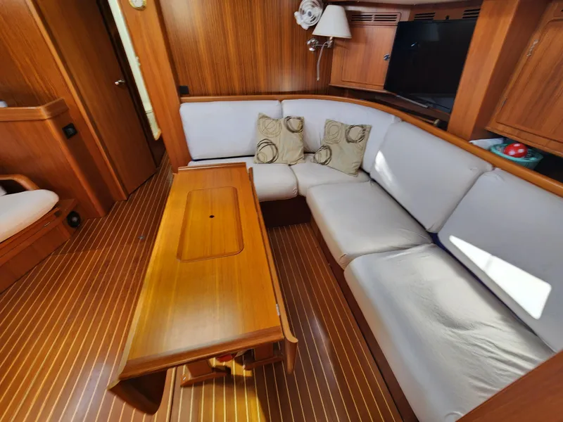 Slide: The Image of Interior of 2006 Hallberg-Rassy 53 yacht with wooden table and white cushioned seating. - 24