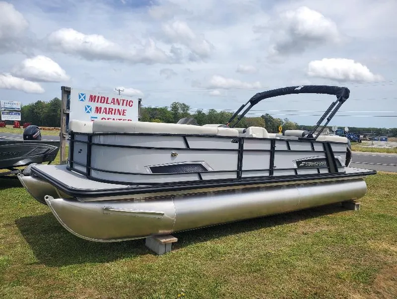 Slide: The Image of 2023 Starcraft EXS-5 pontoon boat displayed at Midlantic Marine, grassy area, cloudy sky. - 0