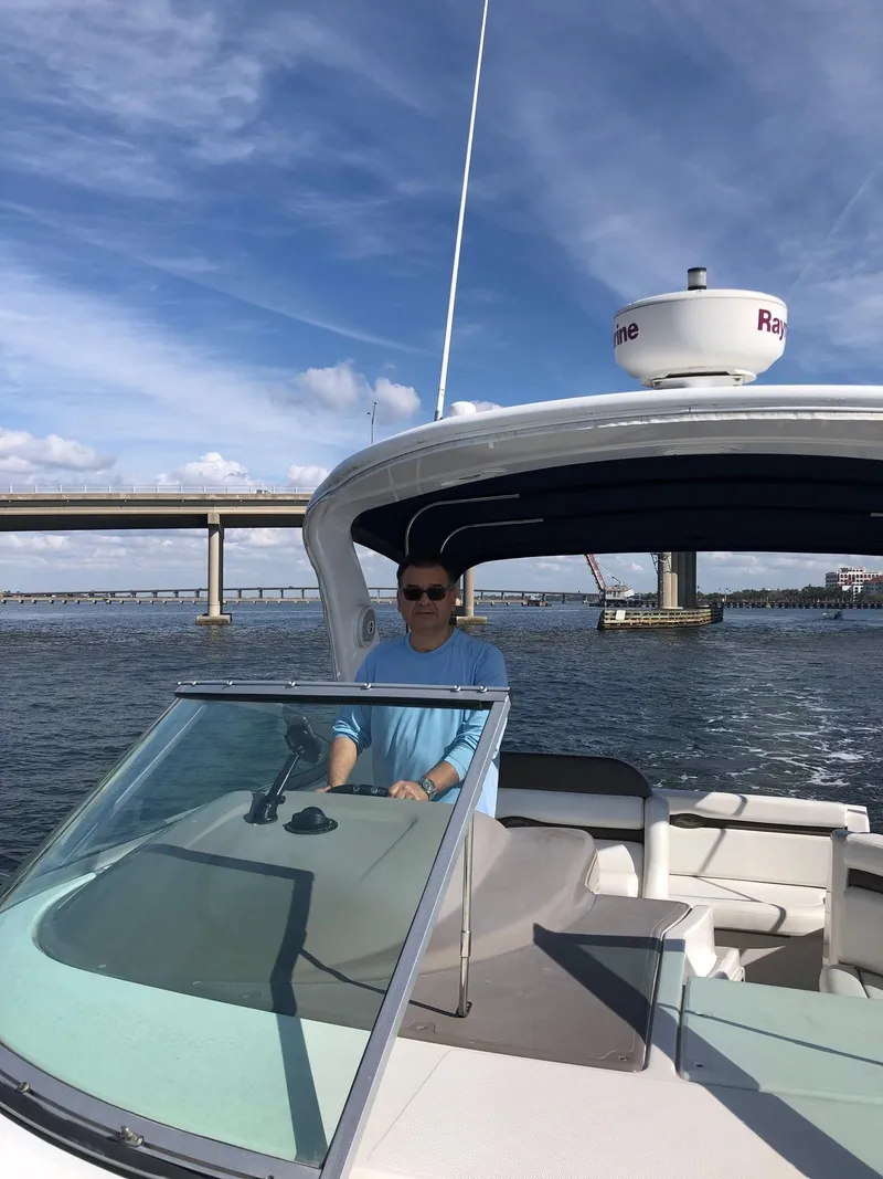 Slide: The Image of Person piloting a 2008 Rinker 350 Express Cruiser on a sunny day near a bridge. - 19