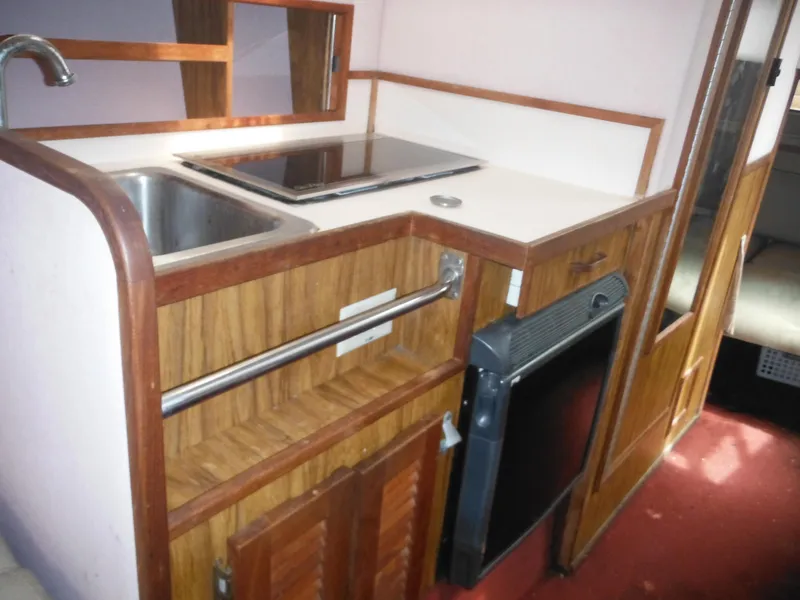 Slide: The Image of 1988 Sea Ray 268 Sundancer boat interior kitchen with sink, stove, and mini-fridge. - 27