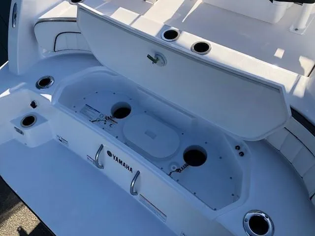 Slide: The Image of 2024 Yamaha Boats 220 FSH Sport, open storage compartment, white interior, cup holders visible. - 18