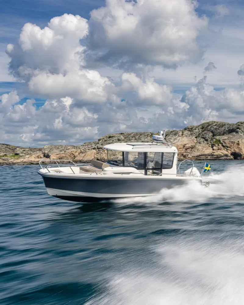 Slide: The Image of 2024 Nimbus C8 boat cruising on open water with rocky coastline background. - 16