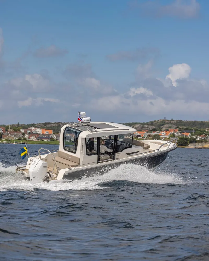 Slide: The Image of 2024 Nimbus C8 motorboat cruising on open water near coastal town. - 3