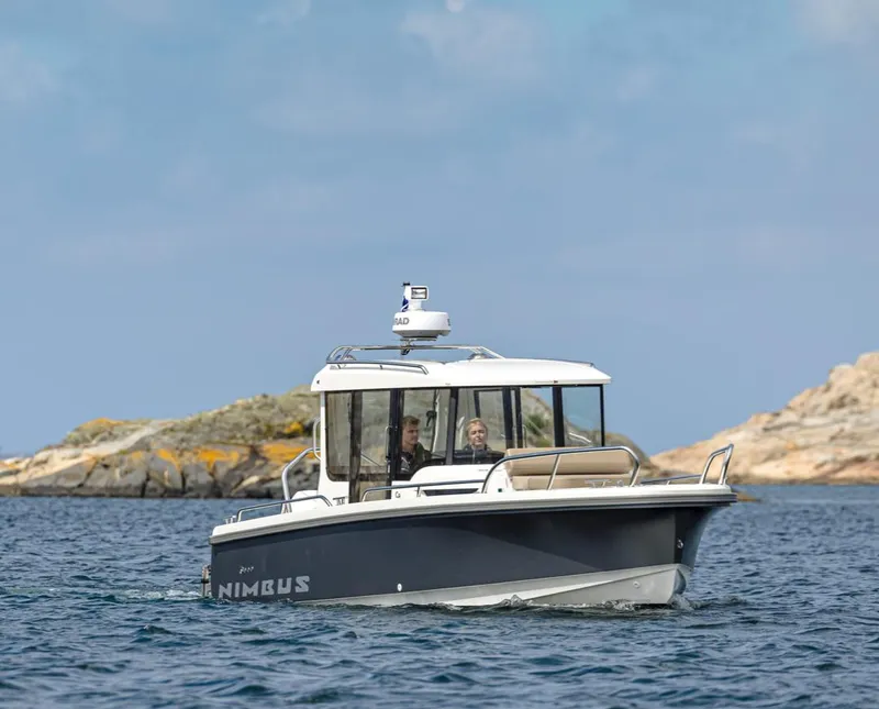 Slide: The Image of 2024 Nimbus C8 boat cruising near rocky shoreline under clear sky. - 11