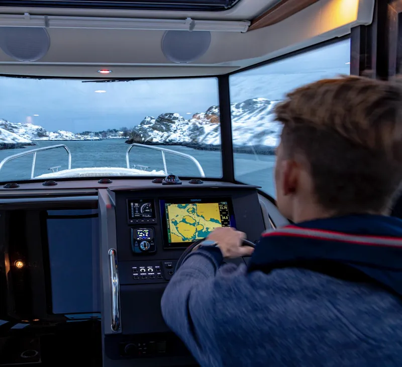 Slide: The Image of Man navigating 2024 Nimbus C8 boat through snowy waters. - 24