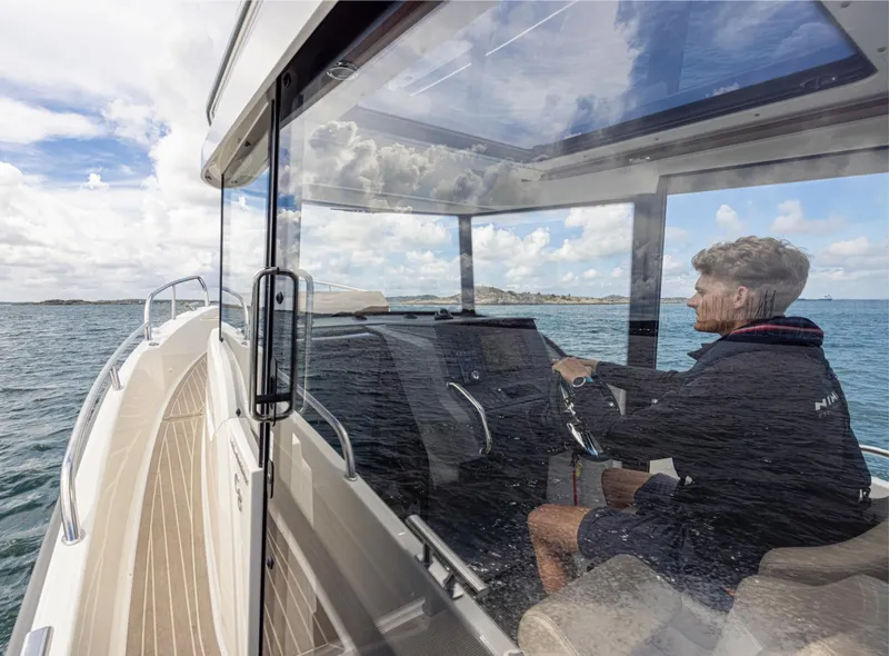 Slide: The Image of Man piloting 2024 Nimbus C8 boat on open water. - 25