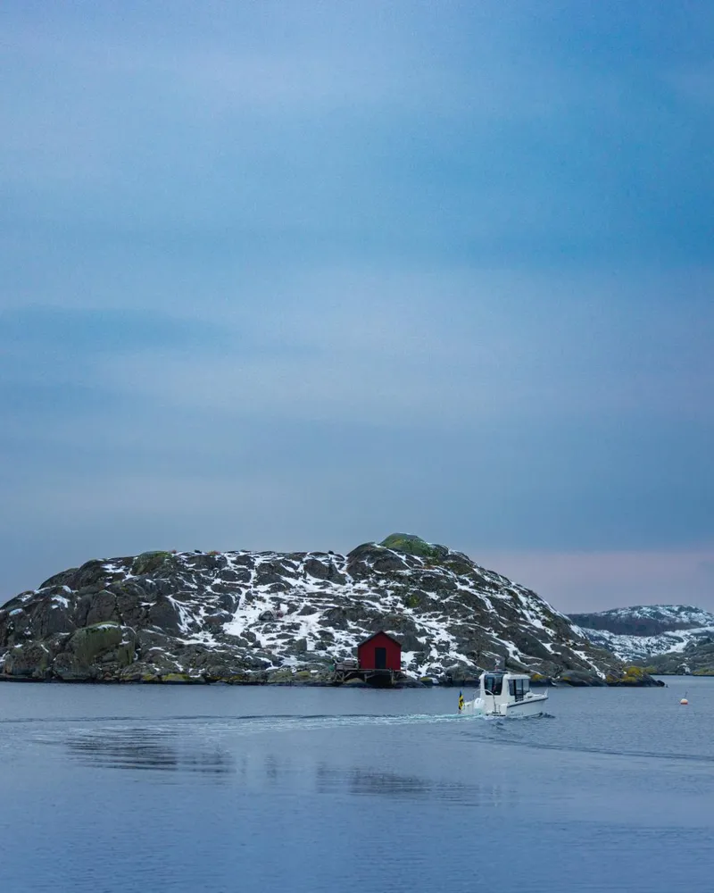 Slide: The Image of 2024 Nimbus C8 boat cruising near a snowy island with a red cabin. - 29