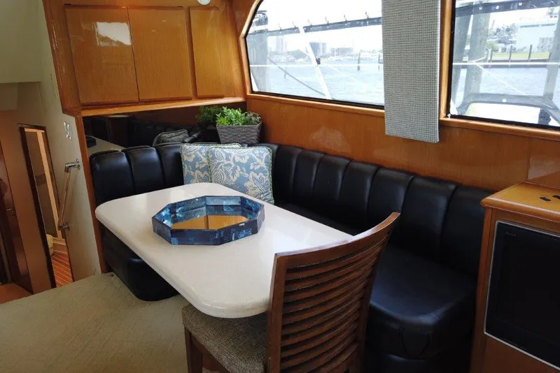 Slide: The Image of 1999 Viking Cockpit Motoryacht interior with dining area, black seating, and decorative accents. - 32