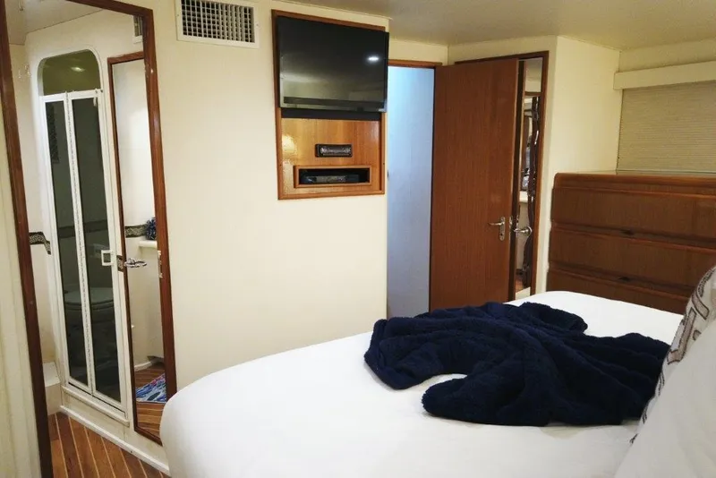 Slide: The Image of 1999 Viking Cockpit Motoryacht bedroom with TV, wooden accents, and ensuite bathroom. - 36