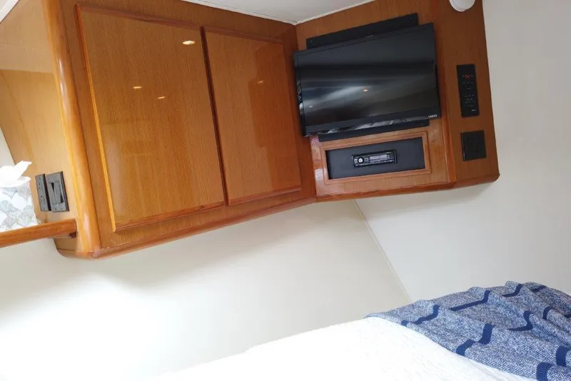 Slide: The Image of 1999 Viking Cockpit Motoryacht interior with TV, wooden cabinets, and cozy bedding. - 43