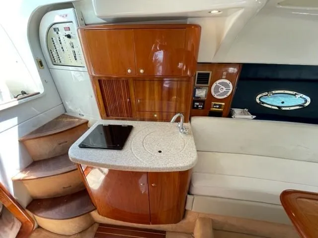 Slide: The Image of 2005 Cranchi 33 Express yacht interior with kitchenette, wooden cabinetry, and stairs. - 4