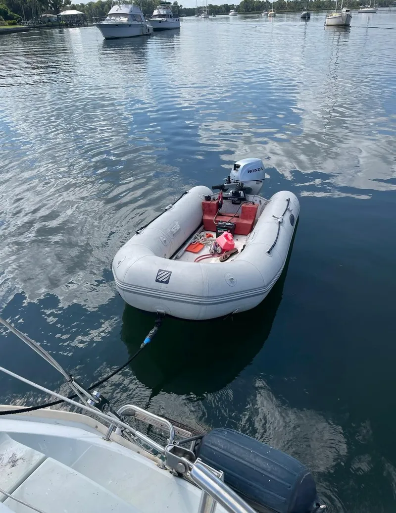 Slide: The Image of Inflatable dinghy tied to a 1990 Beneteau M38 sailboat on calm water. - 10