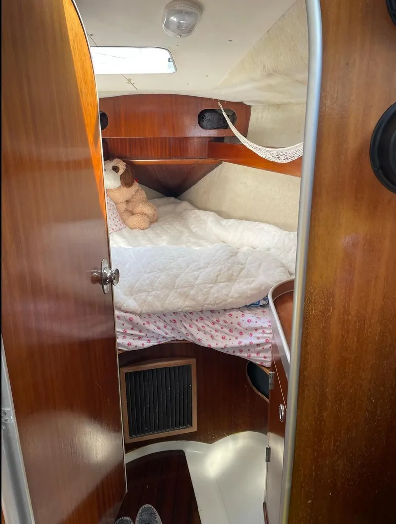 Slide: The Image of Cozy cabin interior of a 1990 Beneteau M38 sailboat with wooden finishes and a plush bed. - 14