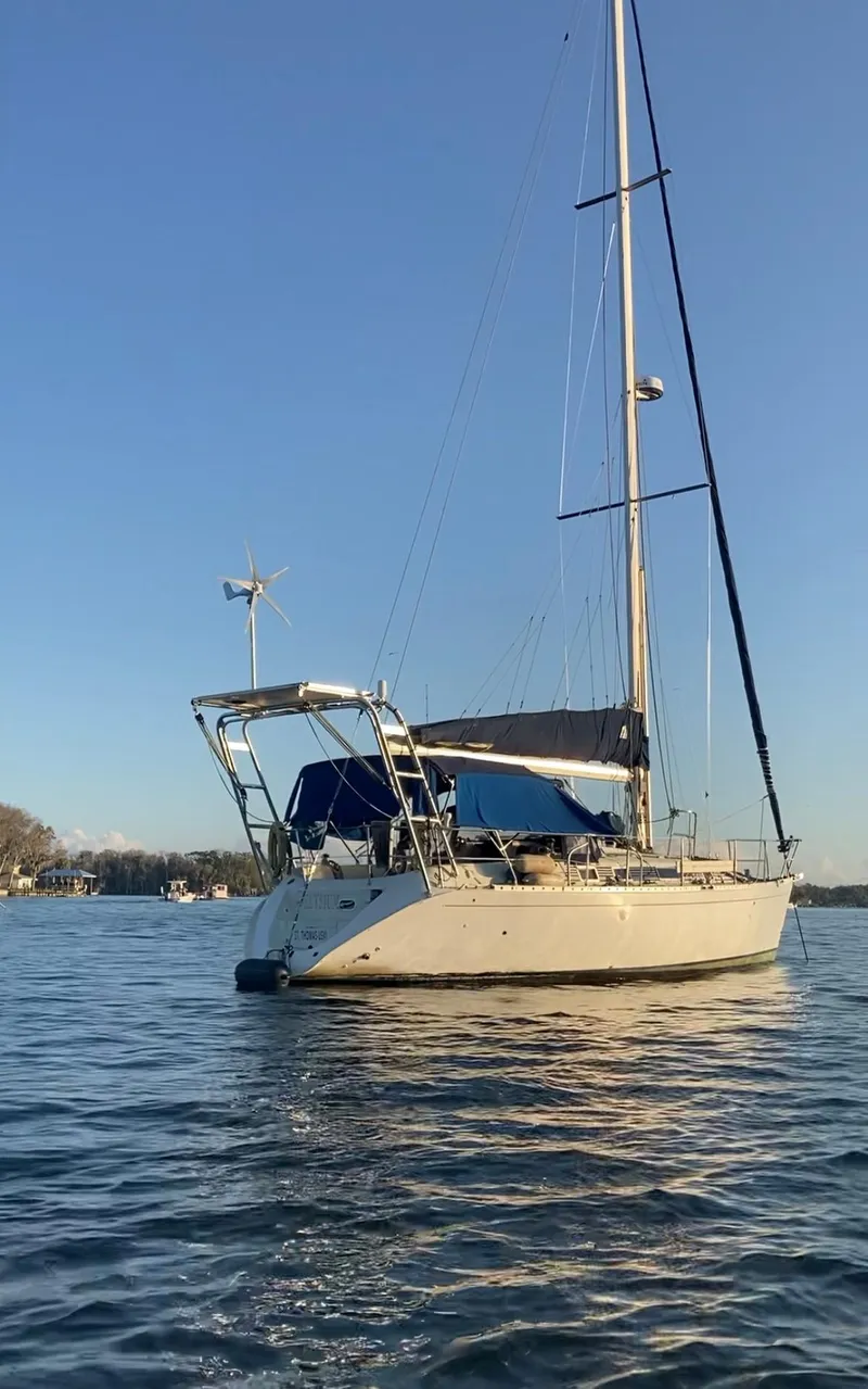 Slide: The Image of 1990 Beneteau M38 sailboat anchored on calm water. - 2