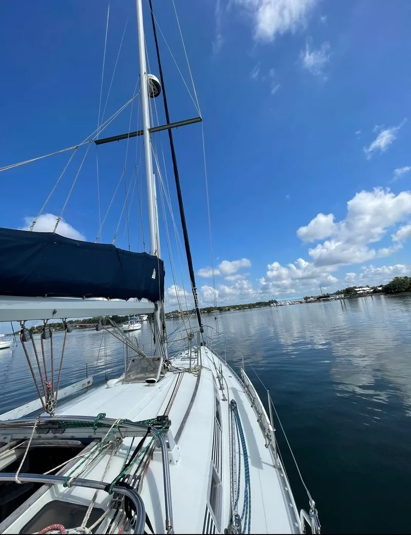 Slide: The Image of 1990 Beneteau M38 sailboat on calm waters under a clear blue sky. - 3