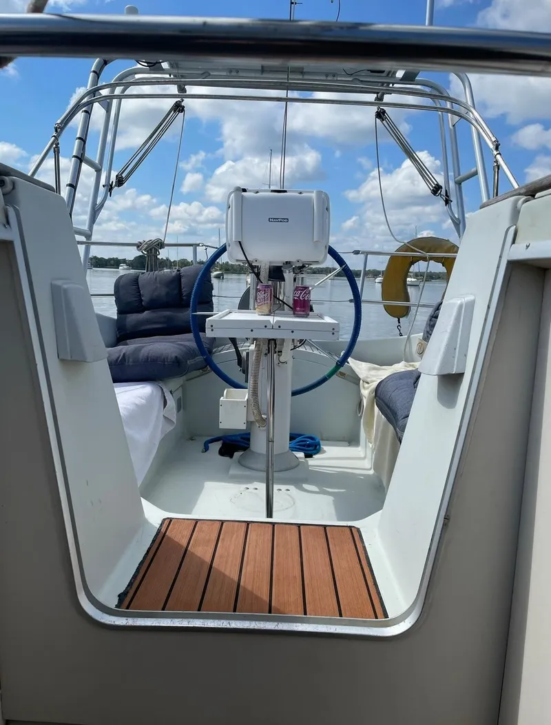 Slide: The Image of Cockpit of 1990 Beneteau M38 sailboat with blue steering wheel and wooden flooring. - 4