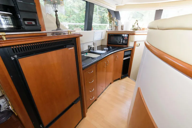 Slide: The Image of 2003 Carver 450 Voyager Pilothouse kitchen with wood cabinetry, black countertops, and appliances. - 8