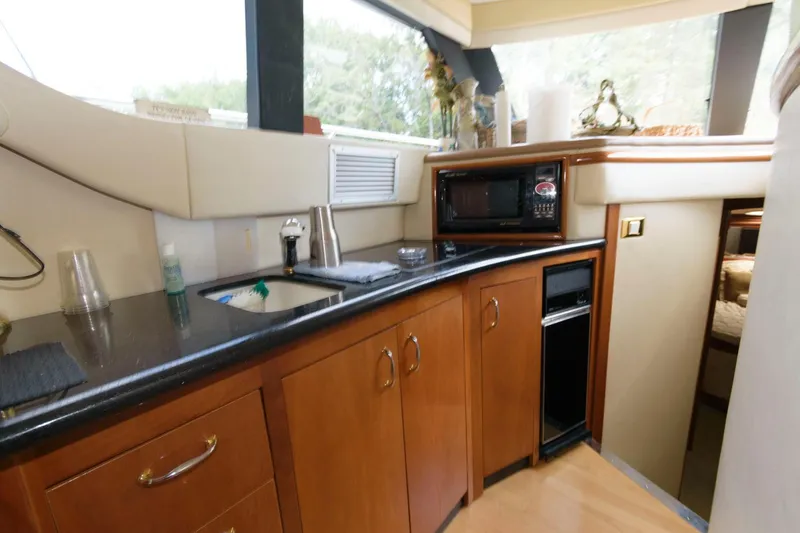 Slide: The Image of Interior kitchen of 2003 Carver 450 Voyager Pilothouse yacht with wood cabinets and black countertops. - 9
