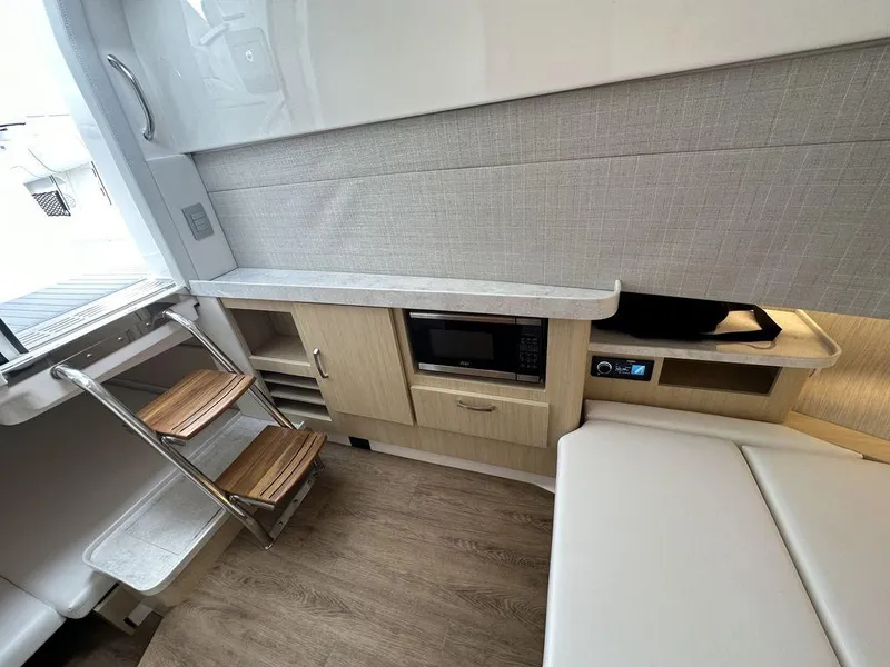 Slide: The Image of 2024 Regal 38SAV interior with kitchenette, microwave, and wooden steps. - 11