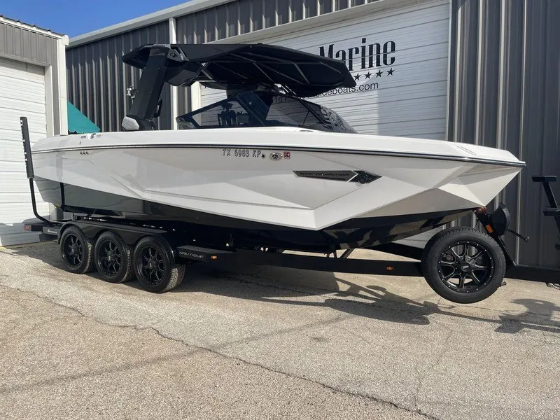 Slide: The Image of 2022 Nautique Super Air Nautique G23 boat on trailer outside marine shop. - 1