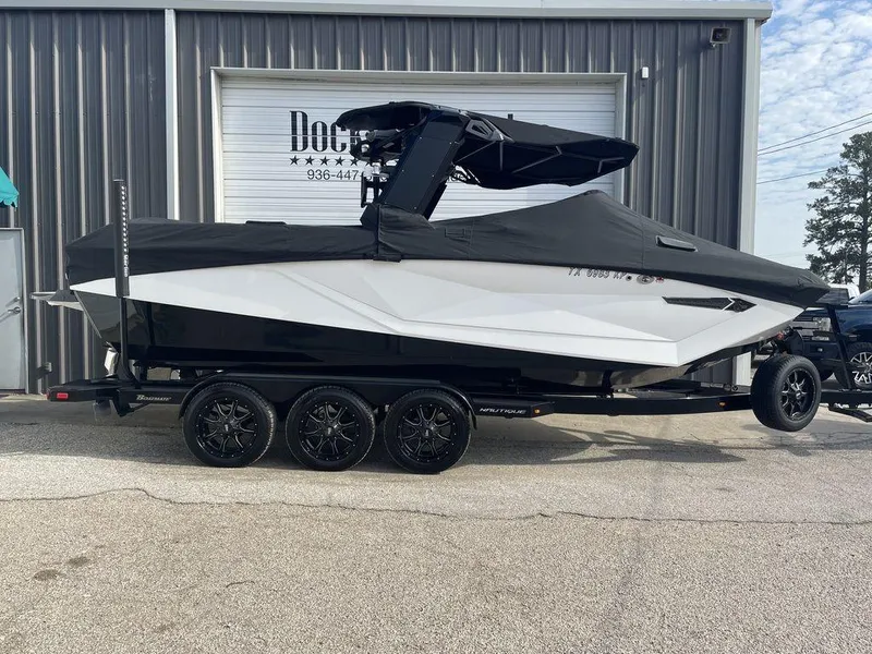 Slide: The Image of 2022 Nautique Super Air Nautique G23 boat on trailer, covered and parked outside. - 2