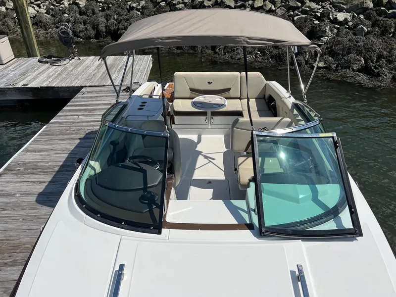 Slide: The Image of 2015 Monterey 268 SC boat docked, featuring a spacious seating area and canopy. - 8