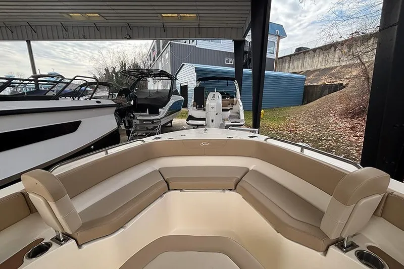 Slide: The Image of 2024 Scout 215 XSF boat interior with beige seating, docked under a shelter. - 21