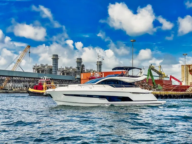 Slide: The Image of 2023 Fairline Phantom 65 yacht cruising near an industrial port. - 3