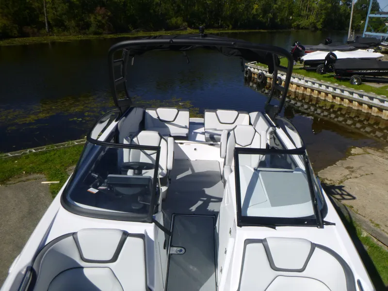 Slide: The Image of 2024 Yamaha Boats AR250, sleek white interior, docked by a serene lake. - 35