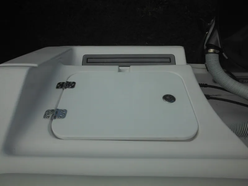 Slide: The Image of 2024 Tidewater 220 LXF boat storage compartment with white hatch and metal hinges. - 18